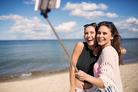 快乐的女人，在海滩上采取自拍照