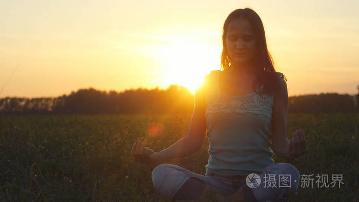 年轻美丽的黑发女人沉思自然,在令人惊叹的日落字段中