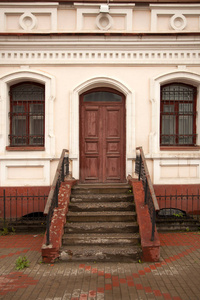 关闭一个木廊与棕色的门和旧的窗户老房子的石头, 画在白色和粉红色的豪宅