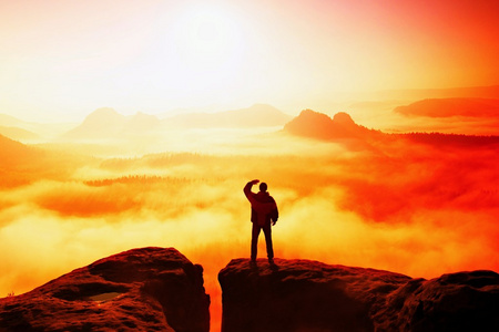 美丽的时刻自然的奇迹。名男子站在的国家公园萨克森瑞士和雾有雾的早晨谷到太阳，注视砂岩岩峰