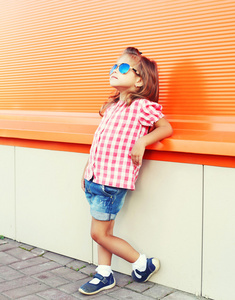 时尚小女孩戴着太阳镜和方格的石