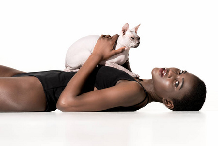 非洲裔美国人的侧面视图穿着泳装躺在猫, 看着相机在白色隔离