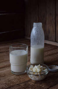 酸乳制品饮料或酸奶瓶中的，来自开菲尔粒和牛奶在木制的背景。与自然光拍摄