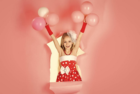 带气球的女孩。小女孩在粉红色背景下玩气球