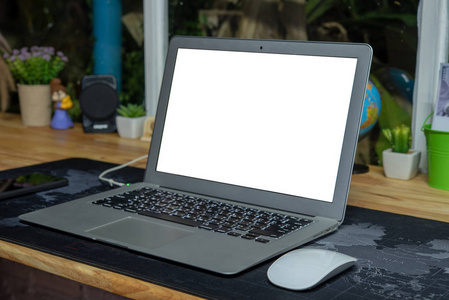 在家里的老式木桌上的空白白色屏幕笔记本电脑。在桌子上的样机白色屏幕笔记本电脑。带空白屏幕笔记本电脑的工作区