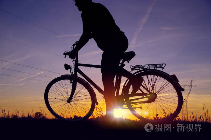 骑自行车的人开始开车日落天空与能量场背景下的复古自行车骑手剪影