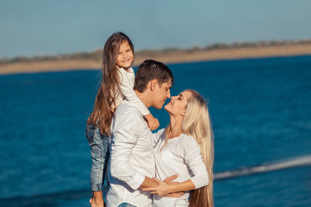 年轻的家庭，在拥抱水的背景上的蓝色牛仔裤