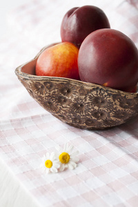 多汁成熟的蜜桃躺在一个手工制作的盘子上的桌布上的