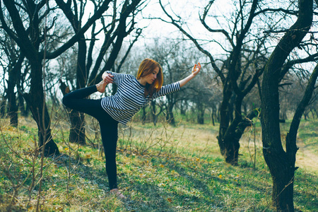 一个漂亮的白人女孩做瑜伽和户外运动。初春时节，东欧