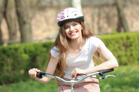 头盔在公园里骑自行车的女孩