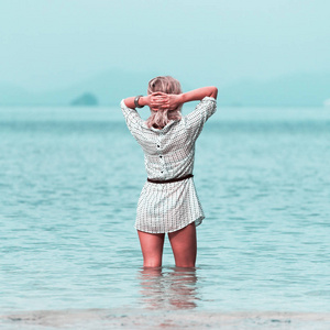 年轻女人站在泰国海滩水中膝盖和欣赏美景