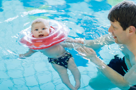 快乐的中年父亲和可爱可爱的宝宝，在游泳池里游泳