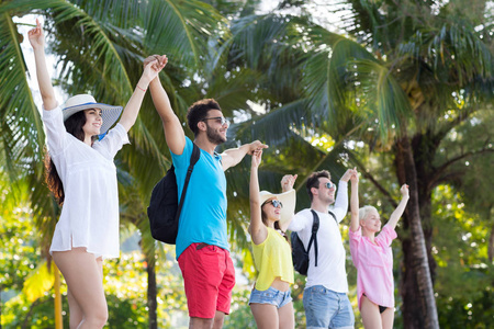 年轻人们集团 控股 举起手来热带公园棕榈树快乐微笑朋友假期暑假