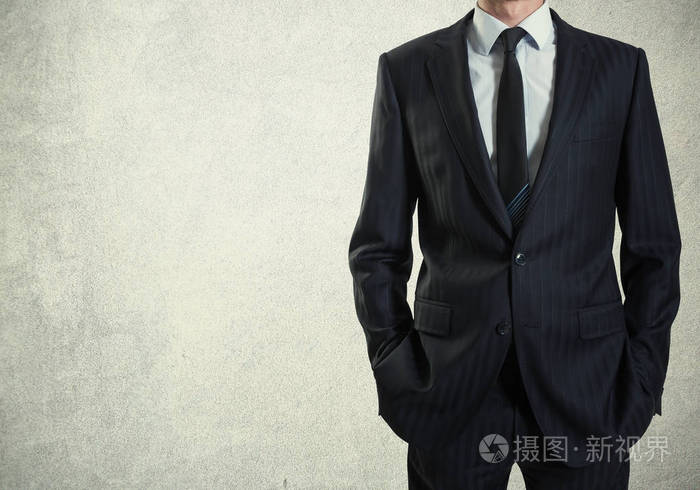在水泥墙背景下穿西装的男人