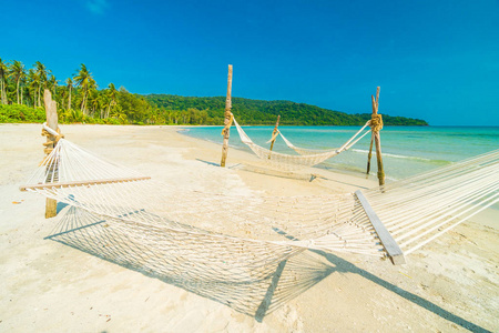 在美丽的热带海滩上的吊床与椰子树和海背景