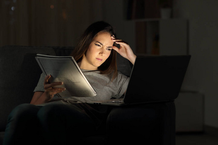 焦虑的学生看在线教程在晚上坐在沙发上的客厅在家里