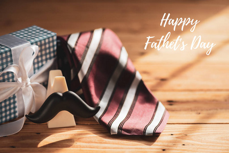 快乐的父亲日概念。彩色领带和礼品盒与胡子在木桌背景