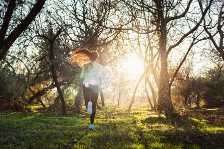 女性在公园跑步。年轻女子慢跑在秋天的树林