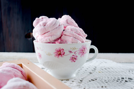 自制的醋栗粉红色棉花糖杯中的西风在白色的木质背景。选择性聚焦