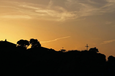 一个金色的日落在城市的丘陵与十字架和屋顶