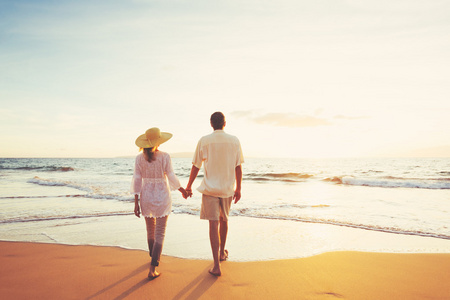 成熟夫妻在日落时分在沙滩上散步