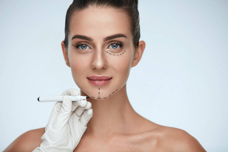 治疗。女人脸上的美容师绘制外科线条