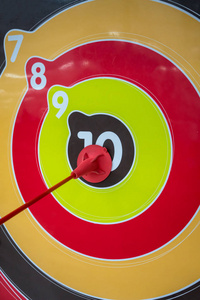 红色塑料箭头与橡胶末端命中在彩色飞镖板的中心以比分10