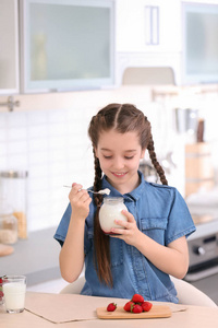 在厨房餐桌上吃可口酸奶的可爱女孩