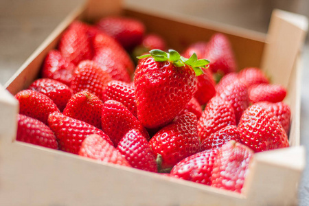 来自西班牙的新鲜和甜美的成熟的红色草莓在厨房柜台。储存在天然的木制塑料盒或箱子里