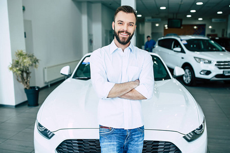 英俊的男子微笑着站在新的现代汽车在经销商, 购买汽车概念