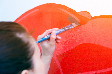 妇女艺术家特写在墙上的一个大木流苏在红色的油漆
