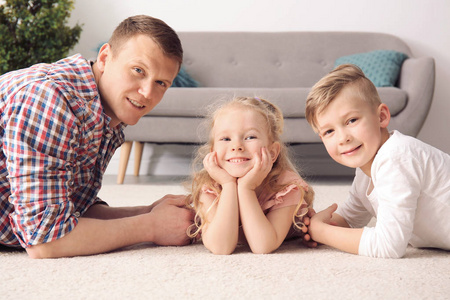 可爱的小孩子和他们的父亲躺在舒适的地毯在家里