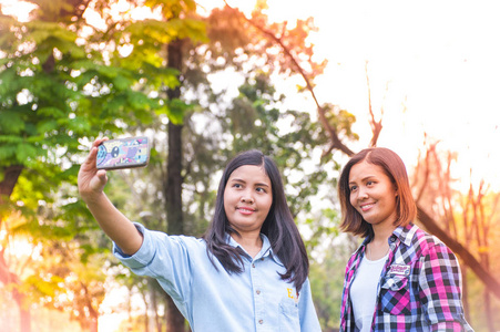 两个年轻亚洲女人制作自拍照摄影在 smartp 上的肖像
