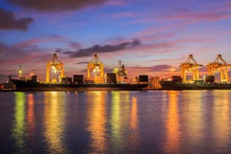 集装箱货运船与工作装卸桥在造船厂在黄昏，物流的导入导出背景