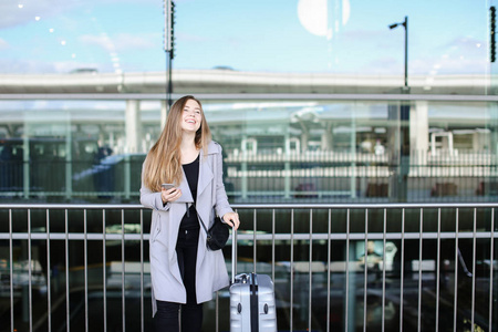 美国女孩站立与手提箱和 smartpone 在机场附近