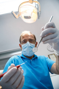 从以下镜头的牙医在制服和手套使用工具和做口腔检查在牙科柜