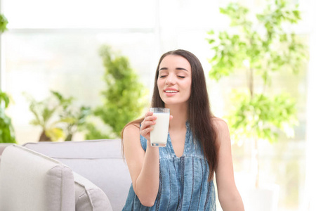 年轻漂亮的女人在家里喝牛奶