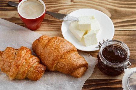 木制桌上的牛角面包黄油和咖啡