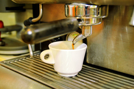 咖啡壶。特写白色咖啡杯。咖啡机。咖啡馆里的专业咖啡壶。咖啡从器具里倒入杯子里。卡布奇诺, 玛奇朵咖啡, 咖啡。热饮料
