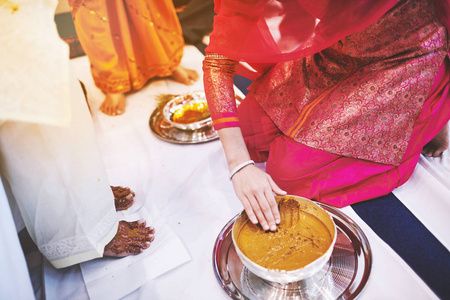 新娘站在白色的织物和妇女 prepraing 姜黄 haldi 油混合牛奶, 以粘贴新娘的脚和身体, 传统的印度婚礼仪式