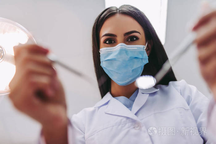 现代牙科门诊牙科工具用医用口罩中女牙医的特写画像