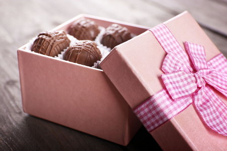 美味的巧克力糖果，在粉红色的礼品盒在木制的背景下，关闭