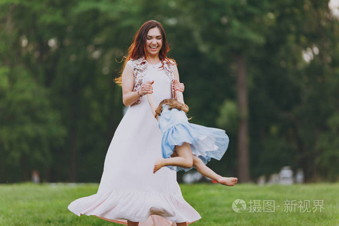 笑女人穿着浅色衣服小可爱的孩子在公园里围着绿草玩耍妈妈小女儿母亲
