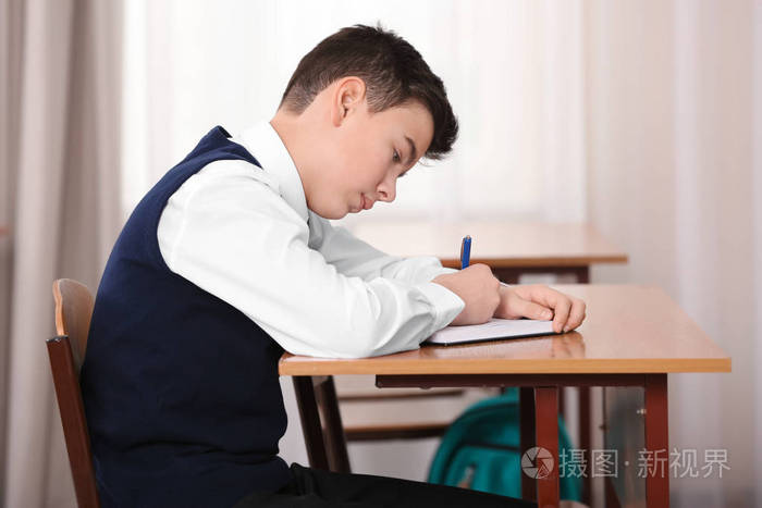 坐姿不正确概念小学生坐在教室的桌子前