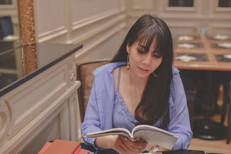 教育理念。亚洲妇女在一家餐馆工作。亚洲妇女正在一家餐馆看书