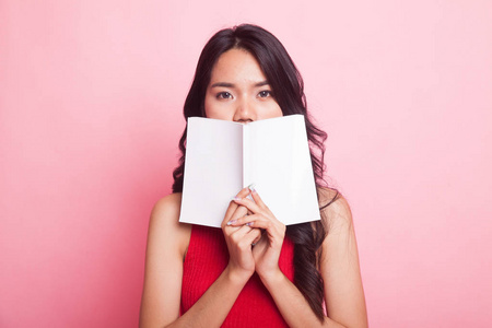 年轻的亚洲妇女与一本书在粉红色背景