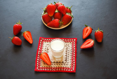 一杯牛奶和草莓在一张黑桌上
