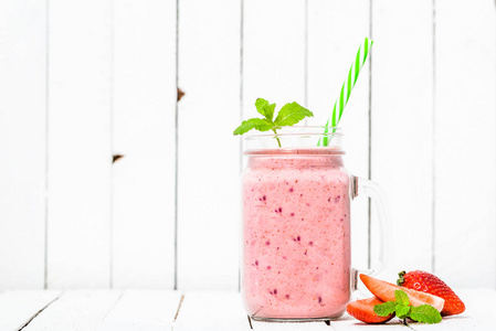 水果奶昔与草莓, 奶昔与草莓混合在罐白色的背景。素食主义饮食与健康生活方式概念