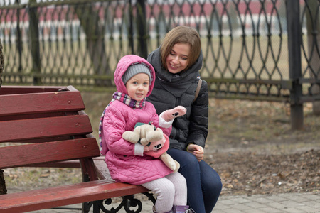 妈妈和女儿正坐在公园的长椅上
