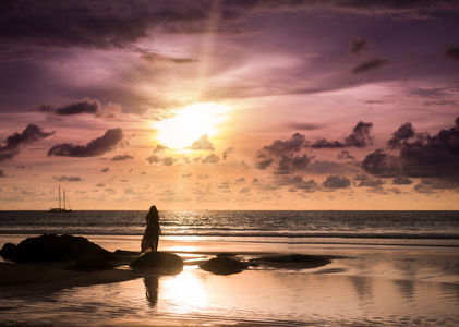 年轻的女人在泰国普吉岛的海滩上看日落